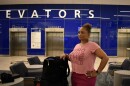 A woman in a pink outfit stands next to her luggage in the main terminal of Tampa International Airport