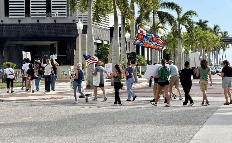 Protesters at the ICE Out Now protest in downtown Fort Myers cross Edwards Drive to gather along Bay Street in front of the Luminary Hotel.