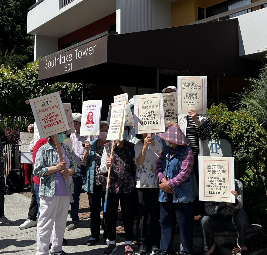 Residents of Southlake Tower picketing the front of the 1501 Alice St Building in Oakland. One picketer is holding a sign reading "CCH is ignoring tenant voices"