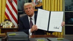 President Donald Trump holds up an executive order commuting sentences for people convicted of Jan. 6 offenses in the Oval Office of the White House, Monday, Jan. 20, 2025, in Washington.