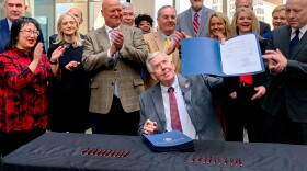 Missouri Gov. Mike Parson, flanked by cabinet members and elected officials, holds up a bill he signed that will increase state worker pay by more than 8% on Tuesday, Jan. 17, 2023, at the Truman Building in Jefferson City.