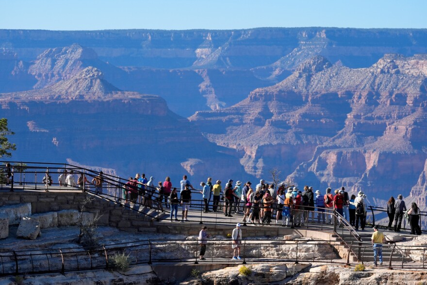 Dozens of tourist stand at the top of the grand canyon. 
