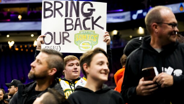 A fan holds a sign that reads Bring Back our Sonics at an NBA game