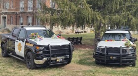 Two Christian County Sheriff's Office vehicles topped with flowers served as a memorial on the Ozark, Mo. square on February 24, 2025.