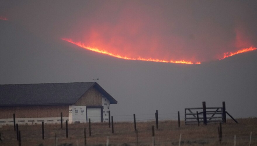 Flames rise from mountain ridges as a wildfire burns near a farmstead late Thursday, Oct. 22, 2020, near Granby, Colo.
