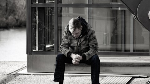 A person sits alone on a bench.