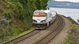 The Amtrak Cascades passenger train running along the bottom of a steep bluff near Steilacoom