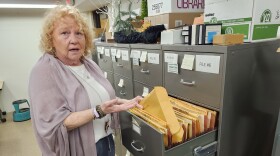 A woman pull a file out of a filling cabinet.