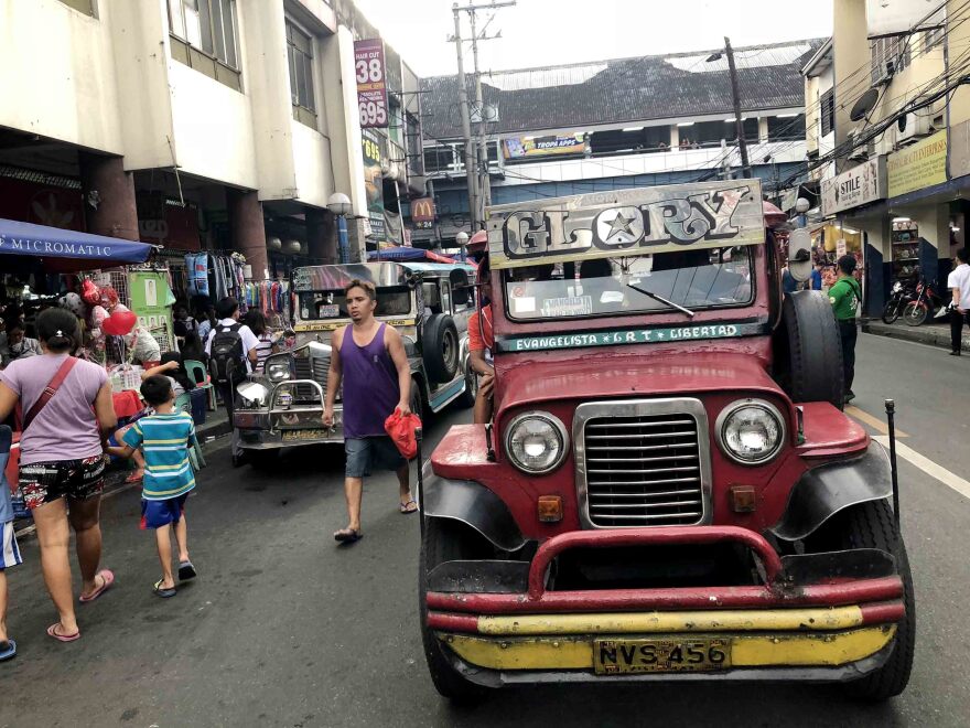 A jeepney crowned with the name "Morning Glory" navigates a Manila street during rush hour. Many jeepneys reach areas of the city where other public transit does not go.