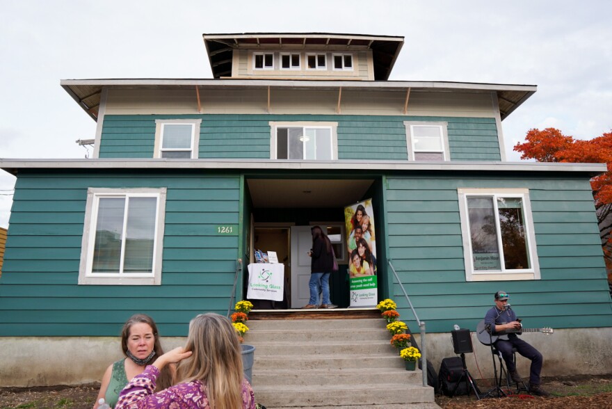 People chat outside a three story house during the grand opening of the Alder House. 