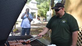 Sgt. Paul Pardue grills up hot dogs for the Alachua County Sheriff’s Office Youth and Community Resource Unit’s “Burger and Books” as Chris Stokes videos the event. (Blake Trauschke/WUFT News)