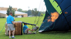 Balloon meister Austin Hopp, crouching, fires up large propane tanks to upright his hot air balloon. He's among 19 pilots planning to fly over the City of Lincoln this weekend as part of its signature Balloons Over 66 festival.