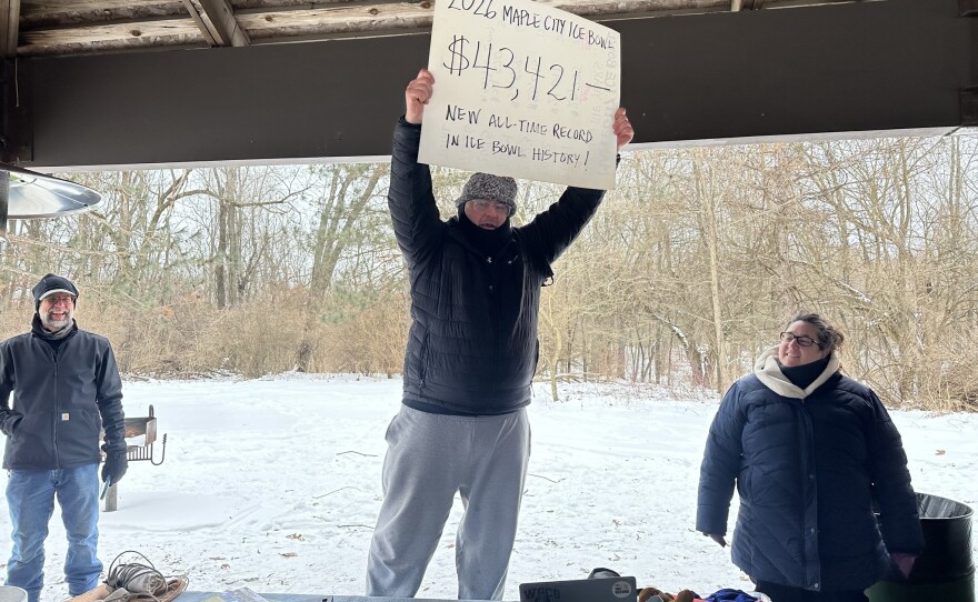 Jason Samuel holds up a poster board showing the $43,421 raised at the Maple City Ice Bowl, a national-record total for a single event.