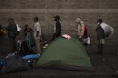 Homeless people wait in line for dinner outside the Midnight Mission in the Skid Row area of Los Angeles, Wednesday, Oct. 25, 2023.