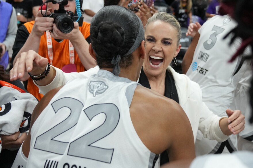 Las Vegas Aces head coach Becky Hammon, right, and A'ja Wilson (22) celebrate after defeating the Phoenix Mercury in Game 4 of the WNBA basketball finals, Friday, Oct. 10, 2025, in Phoenix. (AP Photo/Rick Scuteri)
