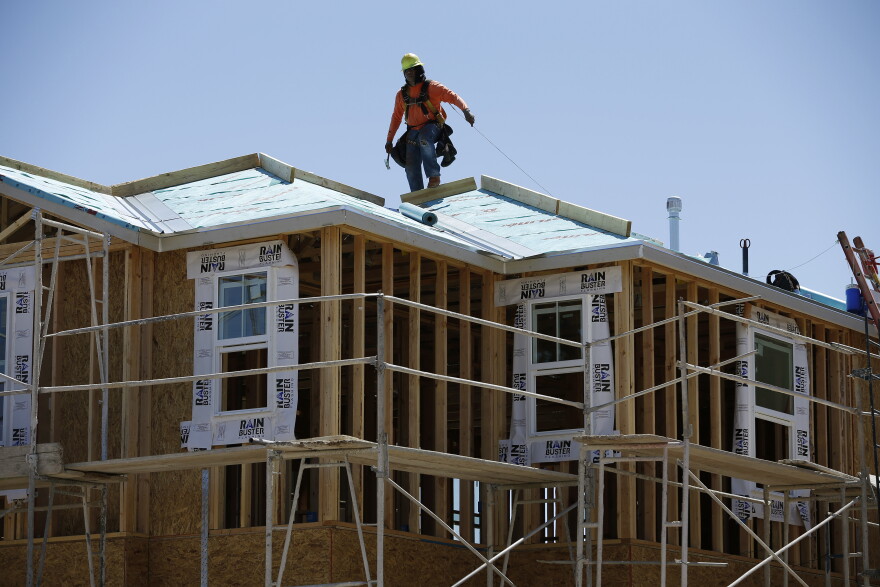 In this April 13, 2015, photo, a worker helps to build a new home at a housing tract in Las Vegas.