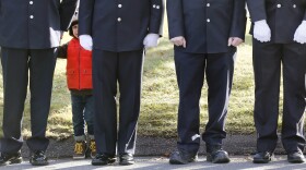 A child peers through firefighters standing as the procession heads to the cemetery outside the funeral for school shooting victim Daniel Barden at St. Rose of Lima Catholic Church in Newtown, Conn.,