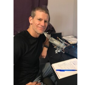 Dr. Chris White sits in front of a microphone.