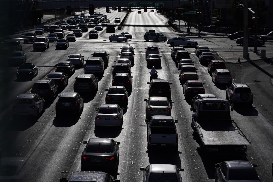 FILE - In this April 22, 2021 file photo, cars wait at a red light during rush hour at the Las Vegas Strip, in Las Vegas.