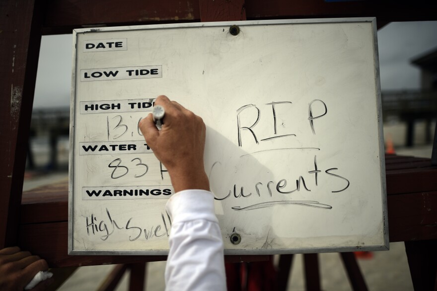 Tybee Island Ocean Rescue Senior Lifeguard Todd Horne writes information on tides and rip currents from Hurricane Arthur to warn swimmers on the beach on, Tybee Island, Ga., Thursday, July 3, 2014.