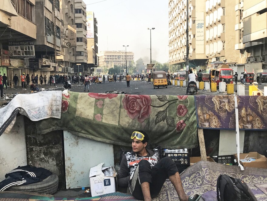 A protester wearing goggles to protect against tear gas sits behind a barricade near Baghdad's Khilani Square.