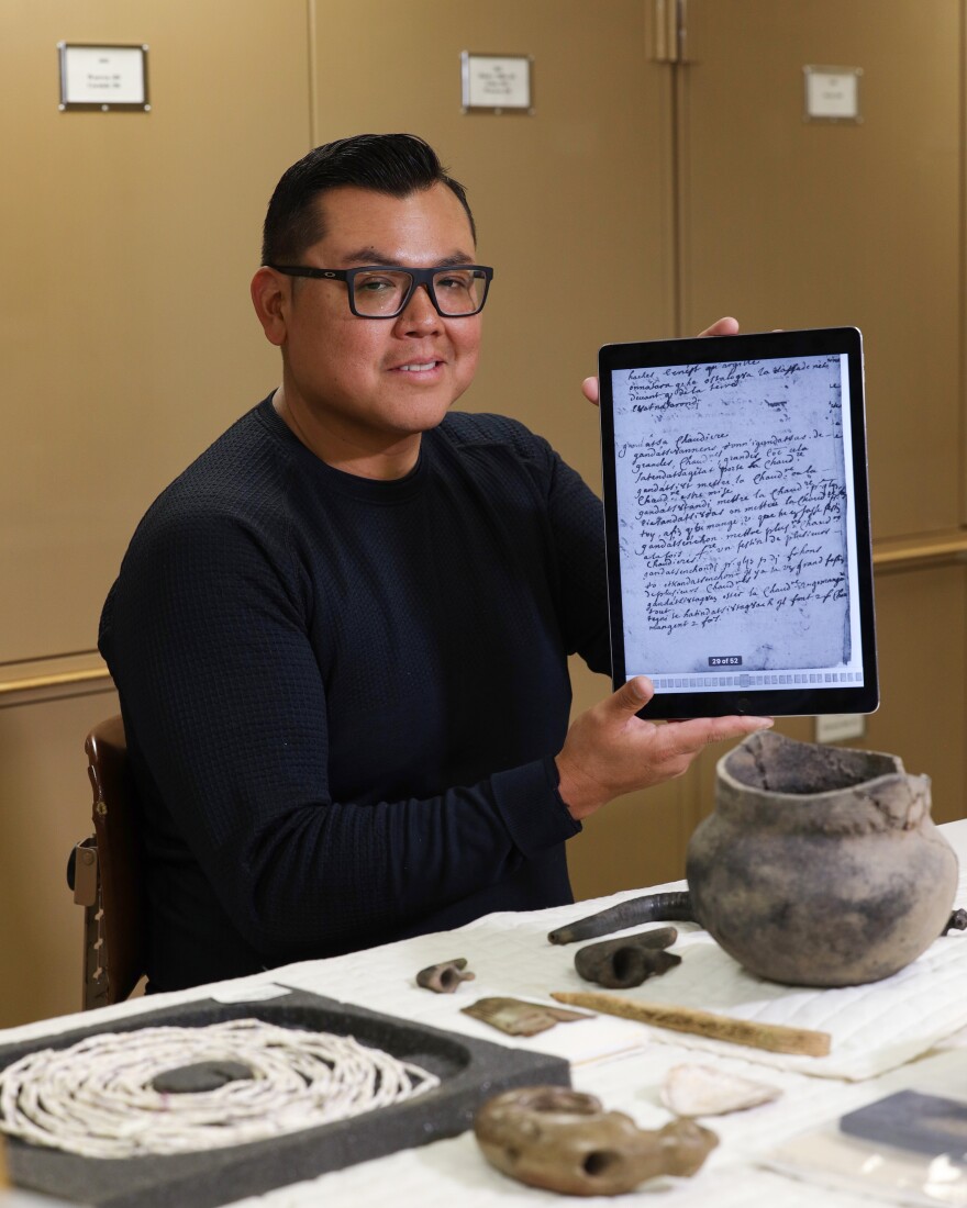 Jamie Jacobs of the Tonawanda Seneca Nation, Turtle Clan, and curator at the Rochester Museum and Science Center for the Rock Foundation works on cataloging Seneca artifacts for an exhibition at the Heard Museum . Jacobs has been linking Seneca art and artifacts to the language through an eighteenth century Jesuit translation of Seneca he references on his iPad.