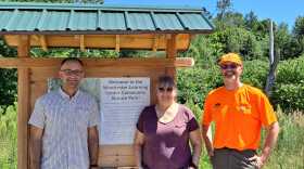 Ryan Owens, executive director (left) and Rick Brackett (right), land manager and GIS specialist, at Monadnock Conservancy and Roberta Royce, Executive Director at Winchester Learning Center, stand in front of the public entrance to the Winchester Learning Center Community Nature Park.