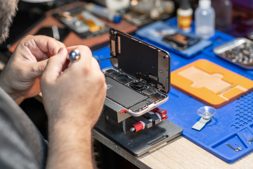 A skilled technician performs phone repair and replaces a battery.