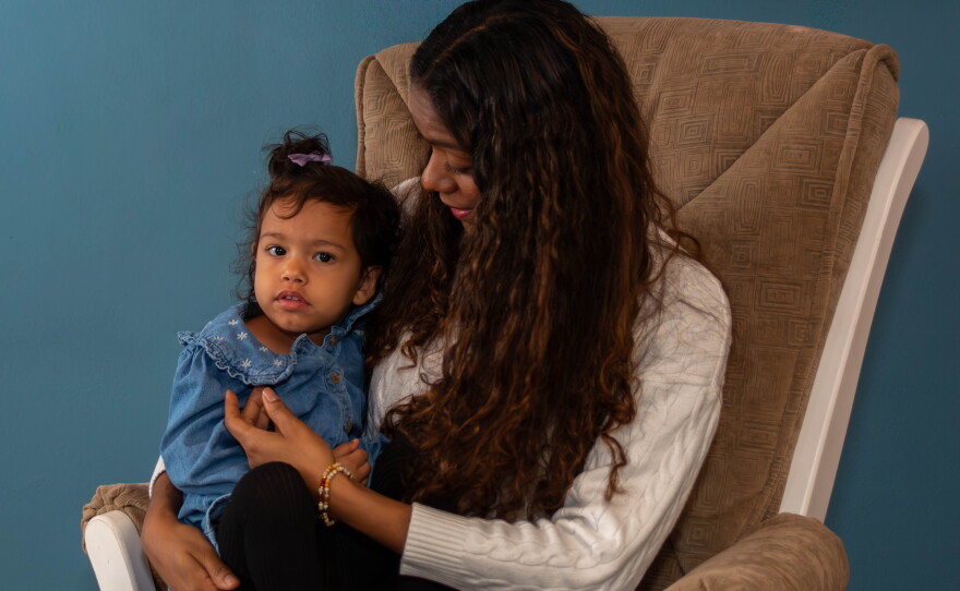 A person sits in a chair with a child on their lap. 