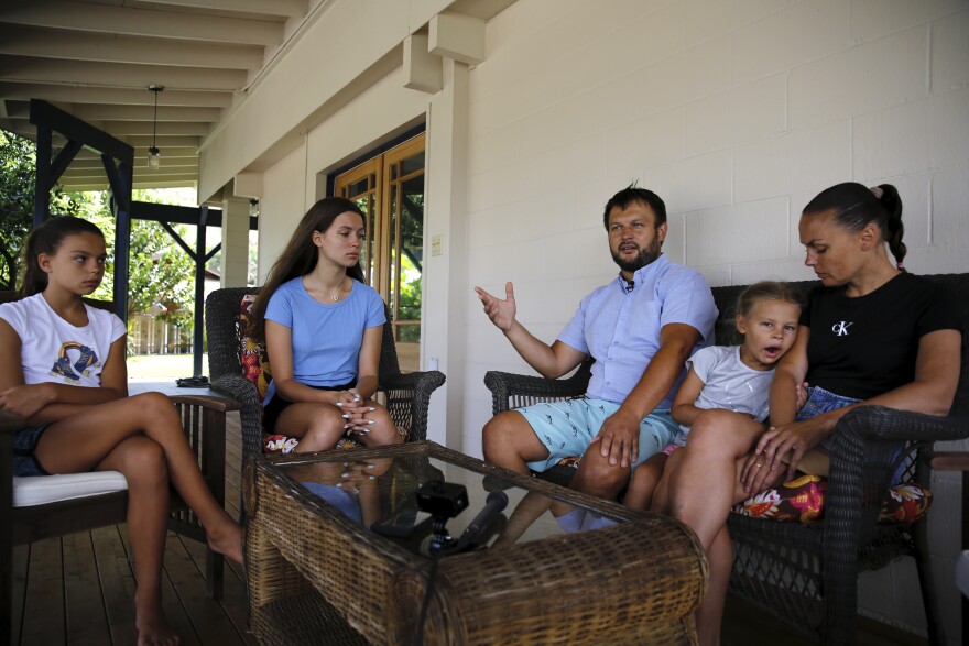 Vasyl Prishchak, center, of Kyiv, Ukraine, speaks to The Associated Press as his wife, Marina, right, and daughters, Ksenia, 5, second from right, Sofiia, 10, left, and Mariia, 16, second from left, listen at their temporary home in Kailua, Hawaiʻi, Wednesday, March 23, 2022. The Prishchak family travelled to Hawaiʻi for a long-awaited vacation on Feb. 16 and planned to return to Ukraine on March 7. But a week into their vacation, Russia invaded their country, leaving the family in shocked disbelief with no access to family, friends, money or their home. (AP Photo/Caleb Jones)
