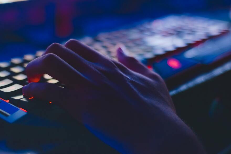 A hand types at a computer keyboard.