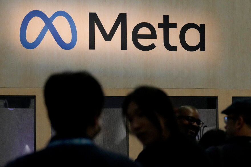 People in front of the Meta logo.