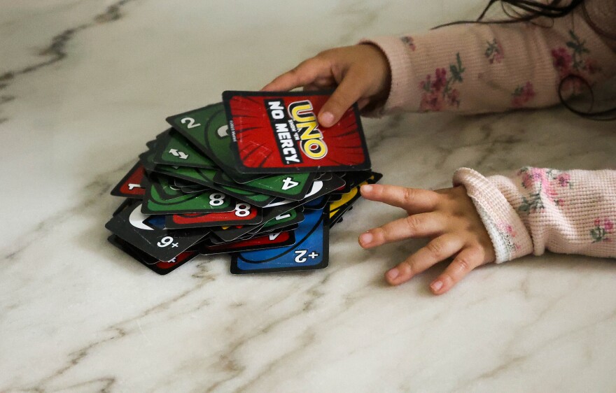Natalia, Sanchez’s toddler, lays down a card as the family plays "Uno, No Mercy Edition."