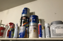 Containers of paint, cleaners and pest control chemicals sit on a shelf in a residential garage.