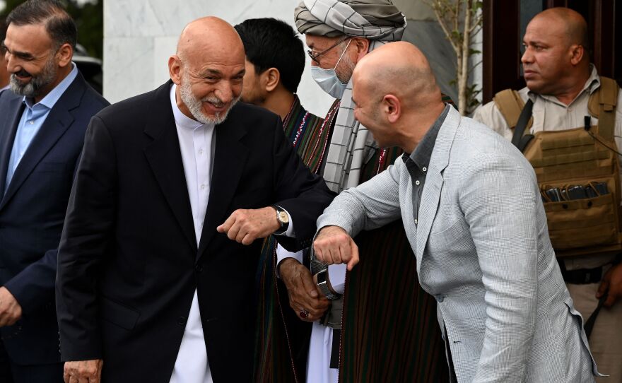 Former Afghan President Hamid Karzai (2L) is greeted by Sadat Mansoor Naderi (2R), the Afghan State Minister for Peace Affairs prior to a press conference at Hamid Karzai International Airport in Kabul on July 16, 2021.