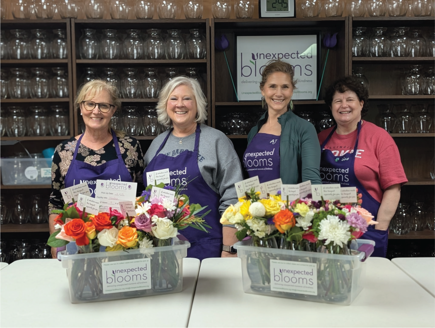 Four florists stand with a display of flowers.
