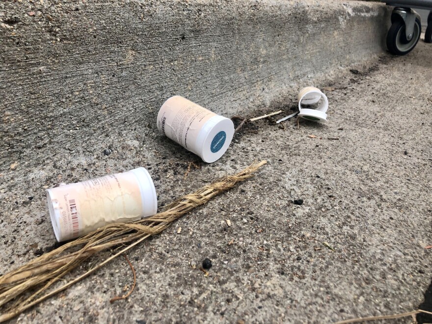 Plastic marijuana dram containers litter a gutter a few blocks from the dispensary