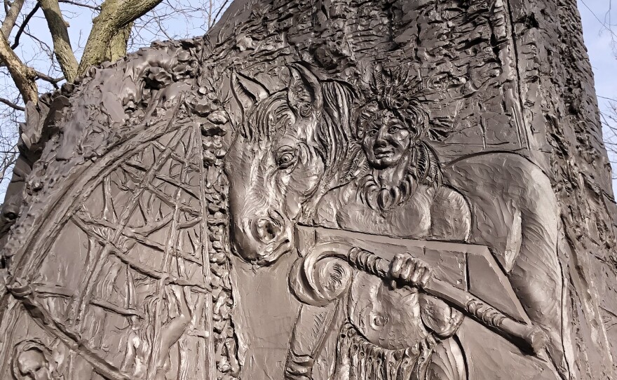 Depictions of indigenous heritage and symbolism are visible on a large bronze sculpture. 