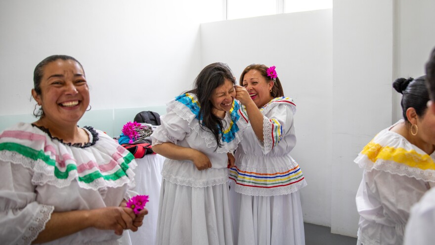 Ruth Infante (second from left), a single mother of three, and her classmates donned traditional flowing dresses for their <em>Cumbia</em> dance performance at a "care block" center in Bogotá, Colombia. The class is one of the free services offered to anyone in the neighborhood who is an unpaid caregiver for their family.