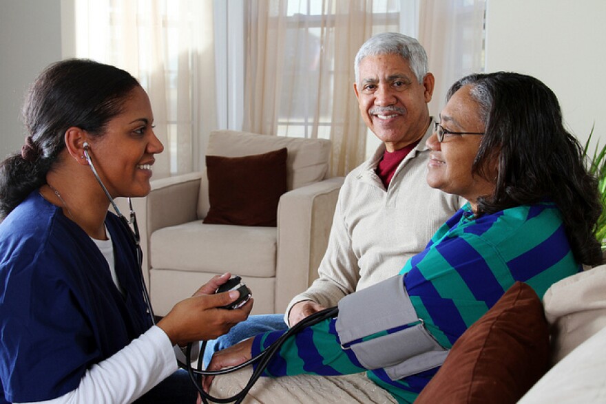 Nurse checking woman's blood pressure while family member watches