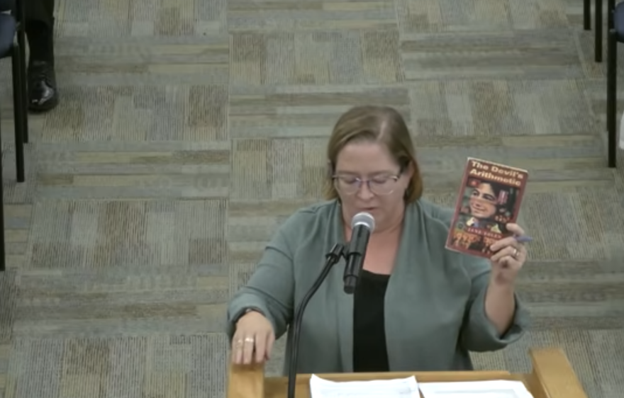 ECPS teacher LeeAnn Eubanks holds a copy of "The Devil's Arithmetic" at the Oct. 20 school board meeting.