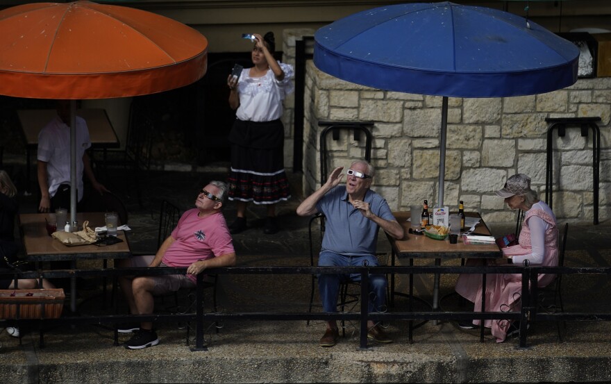 Les convives et les employés des restaurants le long du Riverwalk à San Antonio, au Texas, utilisent des lunettes spéciales pour surveiller le mouvement de la lune devant le soleil samedi.