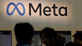 People in front of the Meta logo.