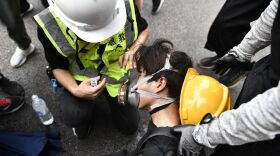 A protester helps a fellow demonstrator after police fired tear gas in the district of Yuen Long in Hong Kong on Saturday. Demonstrators defied a police ban to rally.