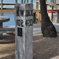 an overseas railroad marker that has been restored and is now located behind a club in key largo