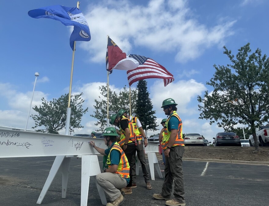 Construction workers sign the final beam before it is set into place