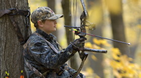 Youth deer hunting with a bow from a tree stand.