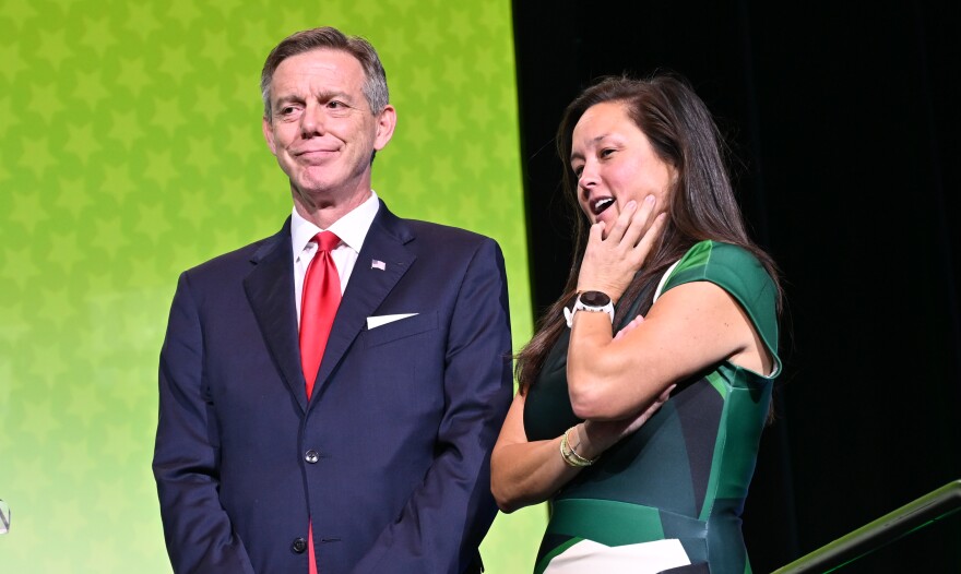 Former Senator Mike Mazzei and House Representative Cyndi Munson stand to the side of the stage to chat as they wait to pose for a picture.