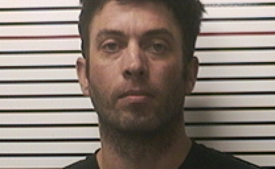 Mugshot of Brian K. Adams standing against a height chart background.