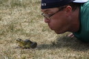 JP Kronschnabel blows on a frog to try to get it to jump during the Wisconsin State Frog Jump in July 2026. (credit: Dan Wanschura / Points North)